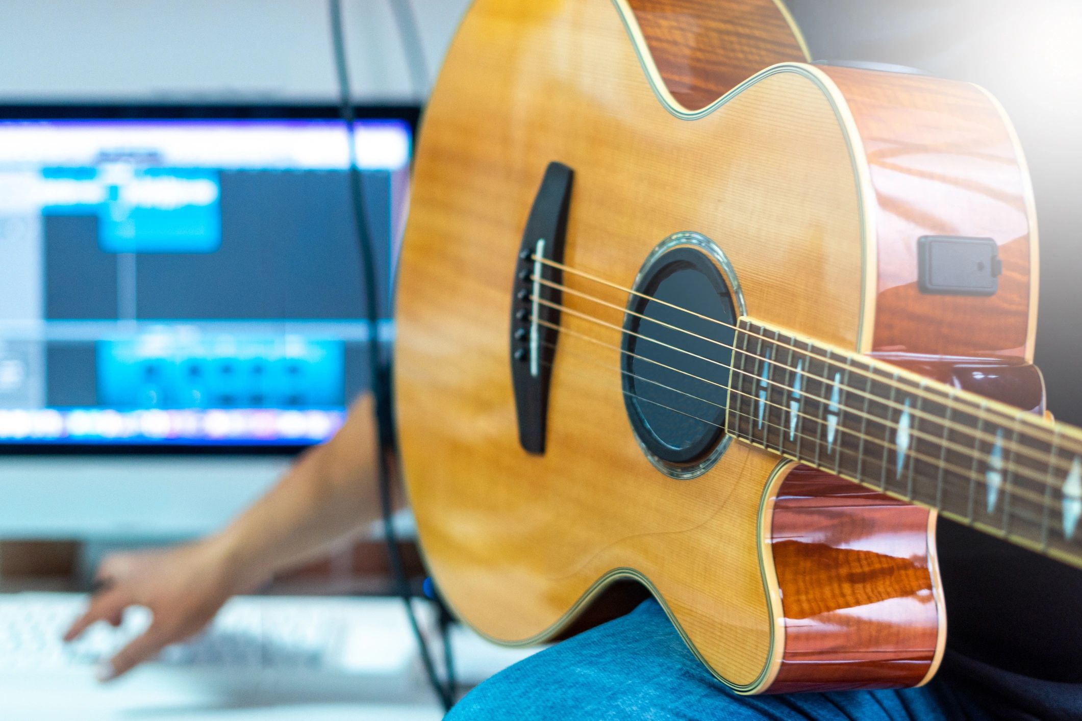 Hands playing an acoustic guitar in a home studio