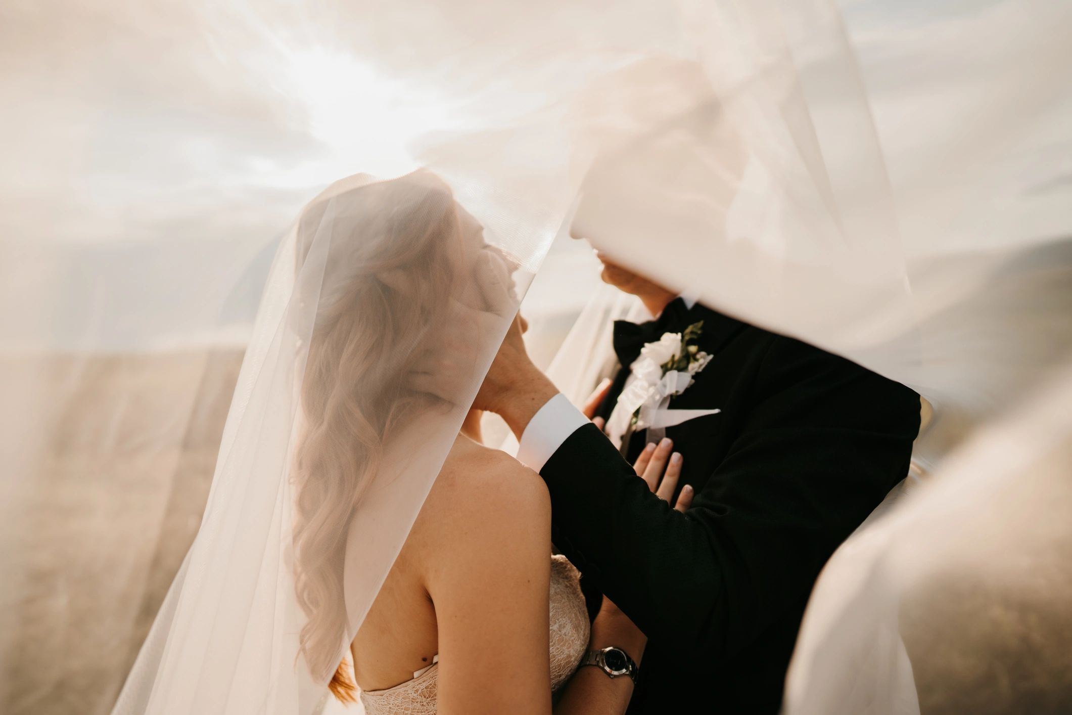 Bride and groom under a veil outdoors