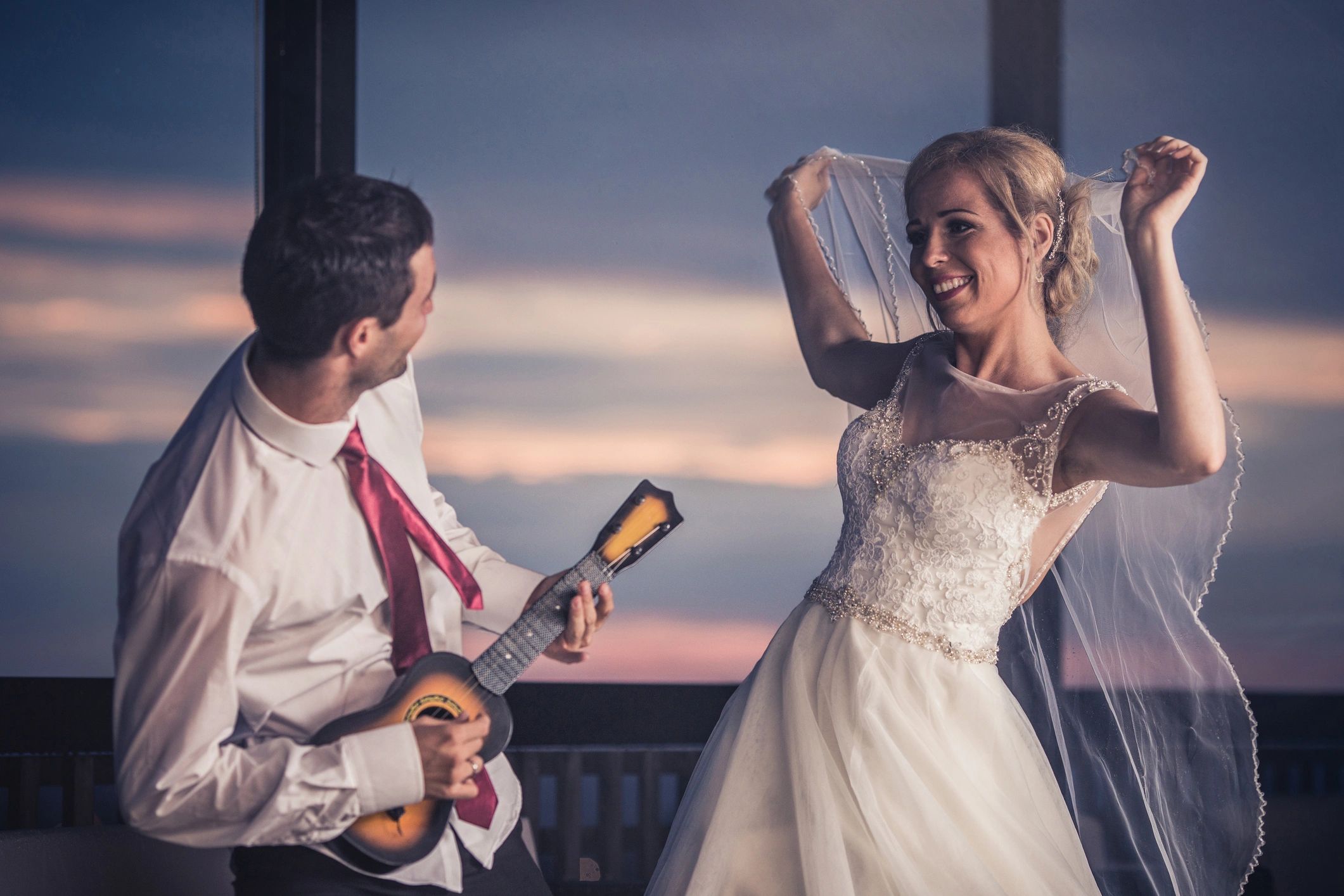 Bride dancing while groom plays acoustic guitar at a wedding celebration
